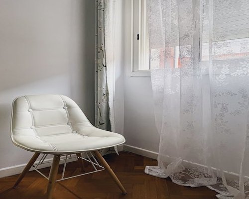 Cozy reading corner by a large window with sheer curtains diffusing natural sunlight